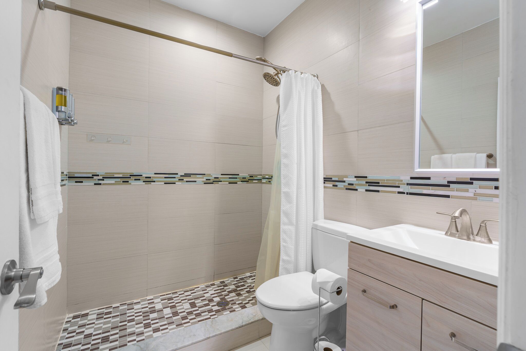 A modern bathroom with a shower, toilet, and sink.