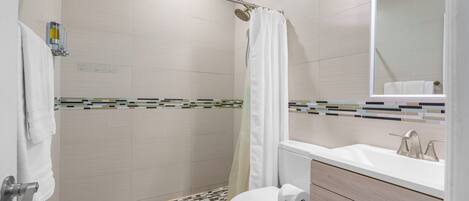 A modern bathroom with a shower, toilet, and sink.