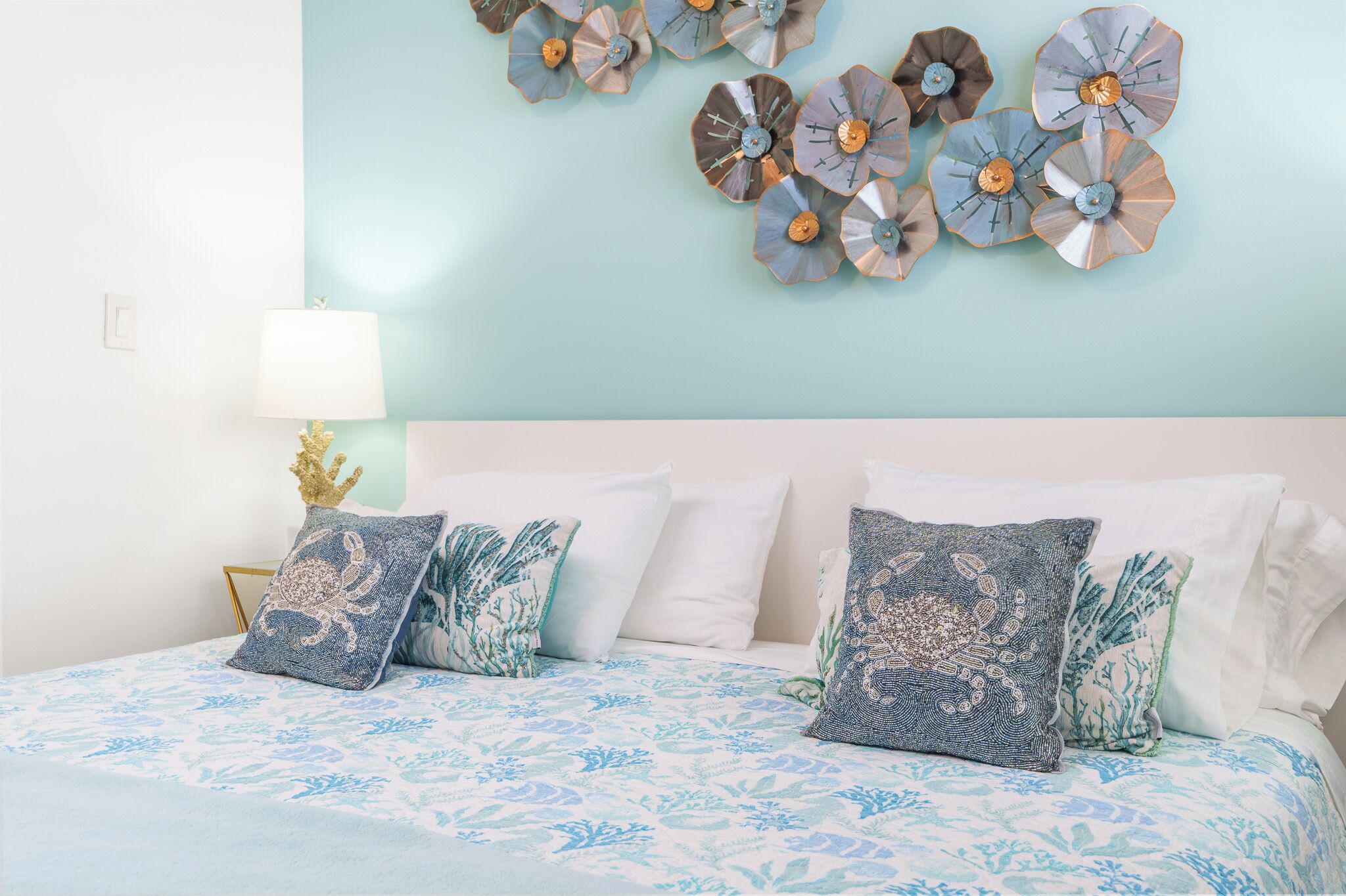 A bedroom with a bed, decorative wall art, and a lamp.