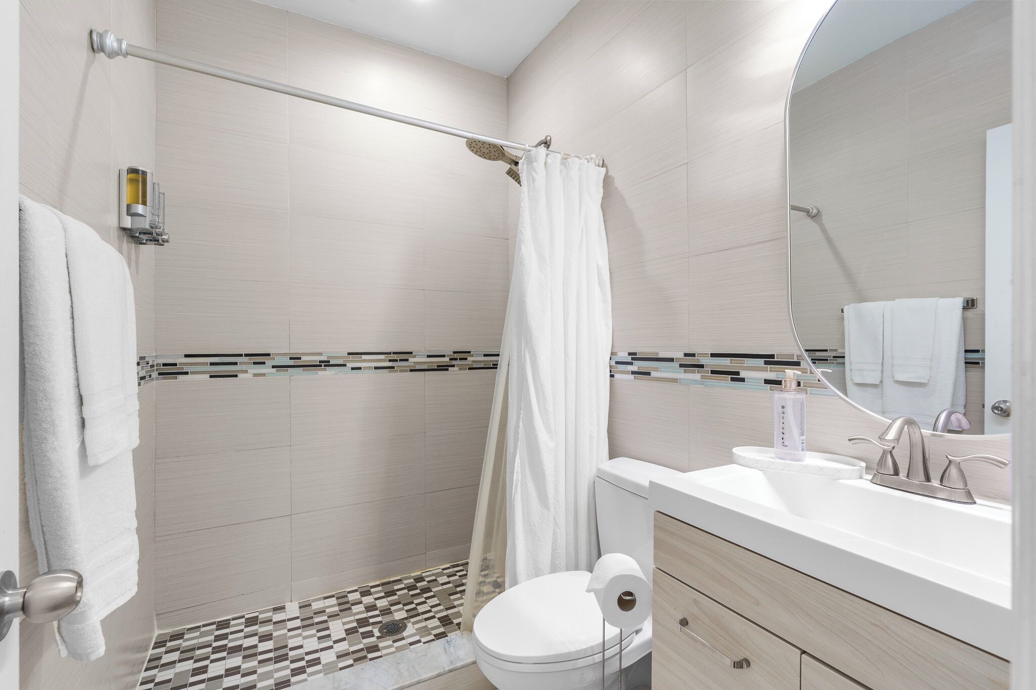 A modern bathroom with a shower, toilet, and sink.