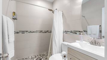 A modern bathroom with a shower, toilet, and sink.