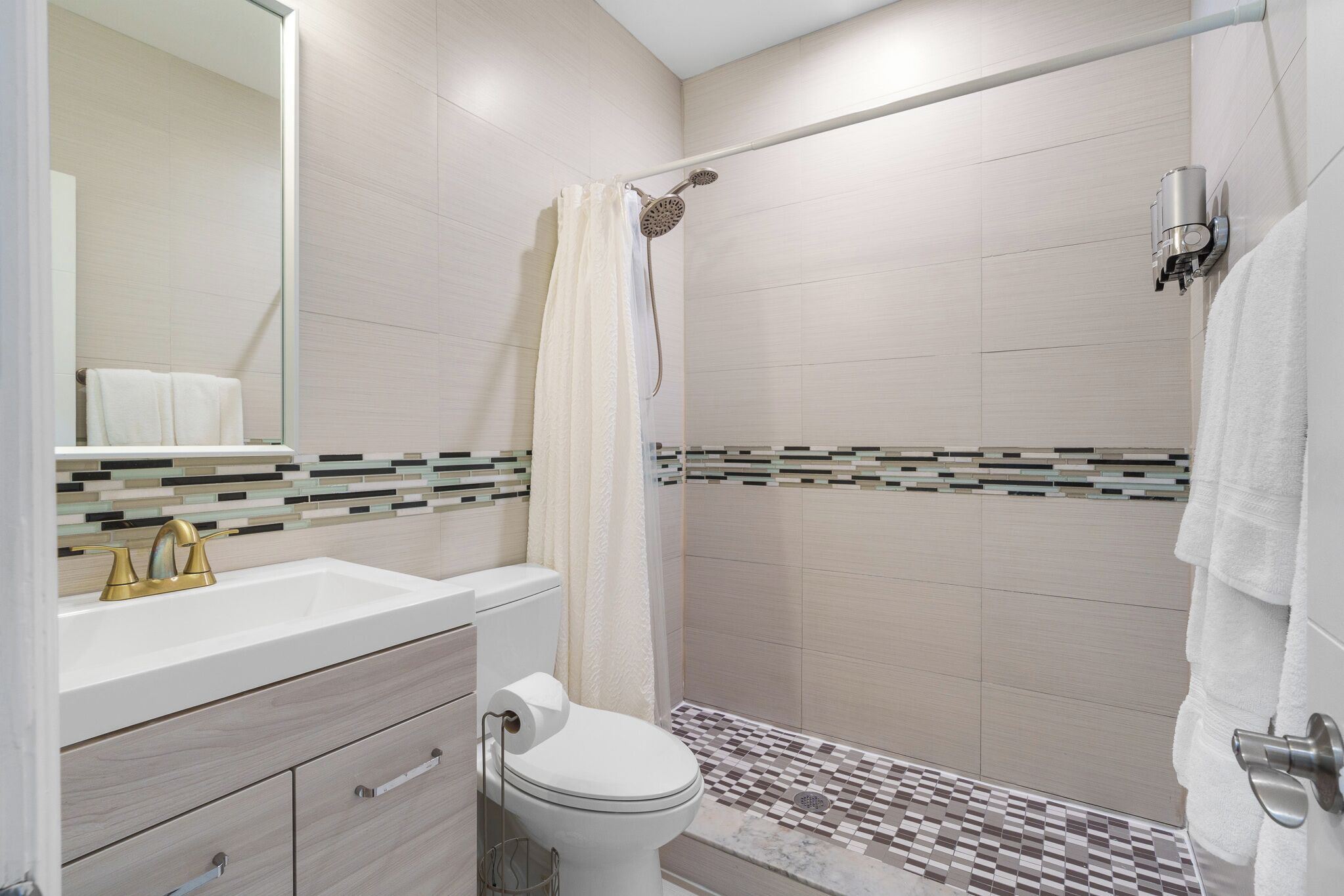 Un baño moderno con un lavabo blanco, grifo dorado y un inodoro.