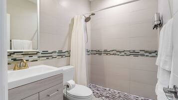 Un baño moderno con un lavabo blanco, grifo dorado y un inodoro.