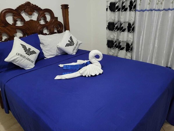 Un lit bien fait, avec des draps bleus, des oreillers blancs ornés de logos et une serviette décorative.