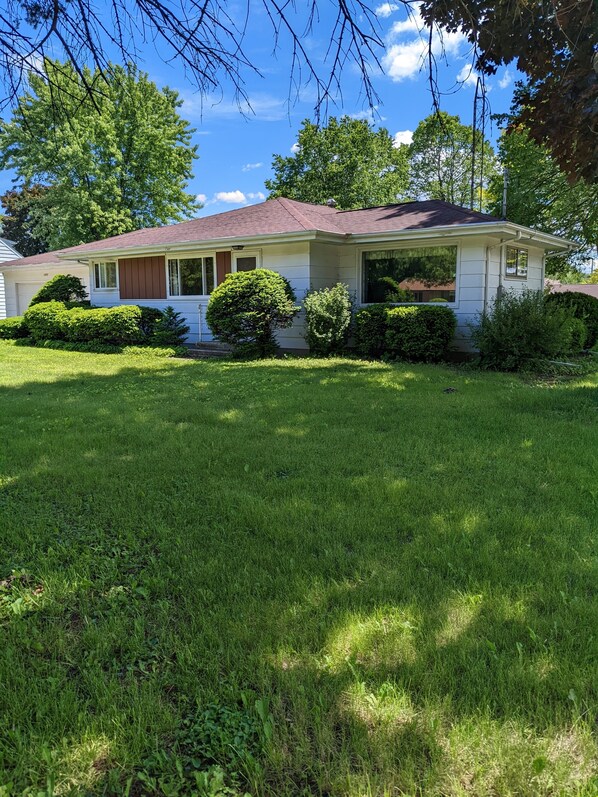 A single-story house with a red roof, white siding, and a covered front porch.