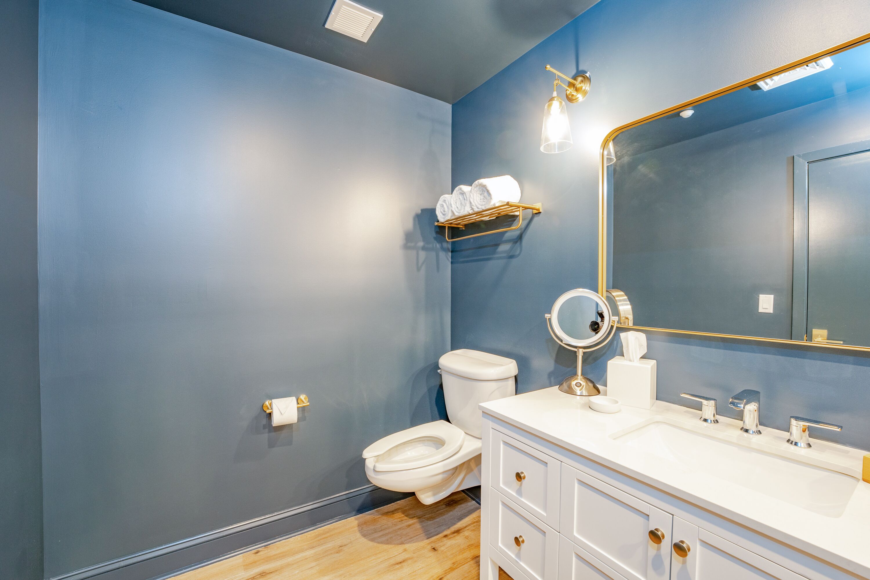Un bagno con il water bianco, un lavandino con rubinetto dorato e uno specchio con cornice dorata.