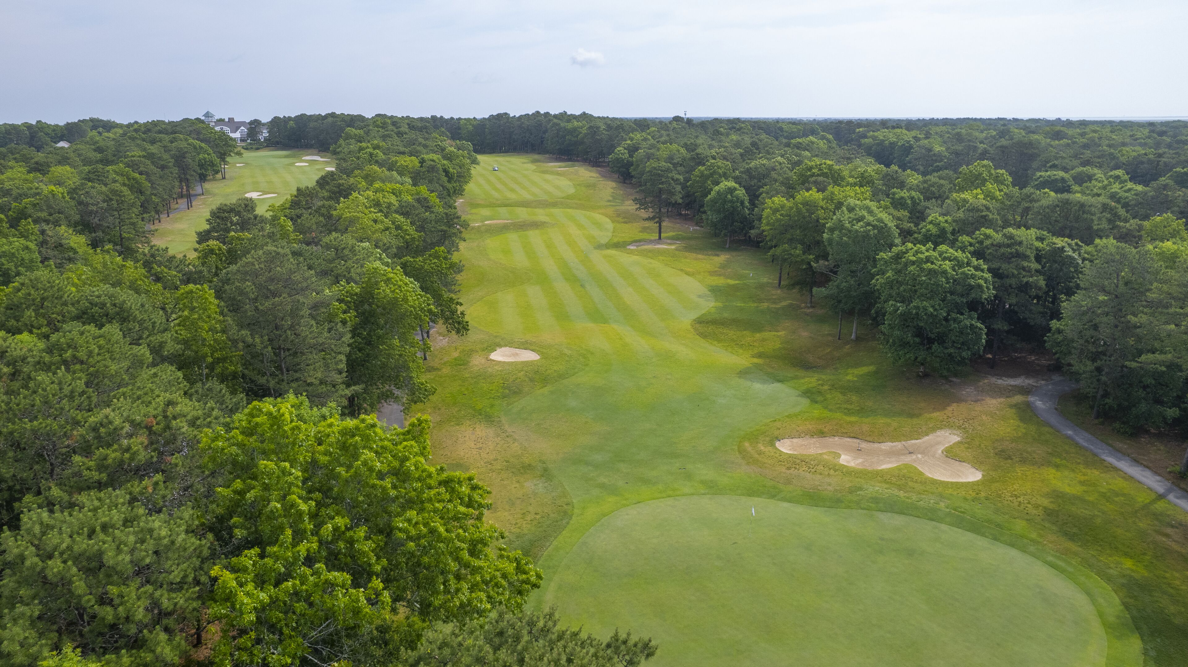 An aerial view of a golf course surrounded by dense forests.