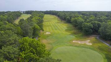 An aerial view of a golf course surrounded by dense forests.