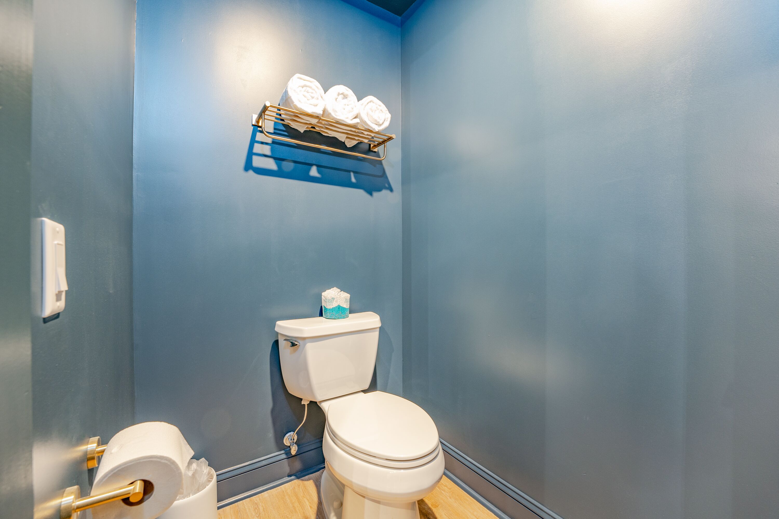 Un baño con inodoro, toallero con toallas y dispensador de papel higiénico.