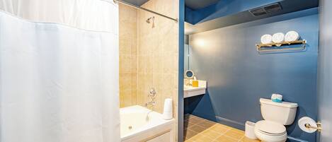 A bathroom with a bathtub, toilet, and a shower curtain.
