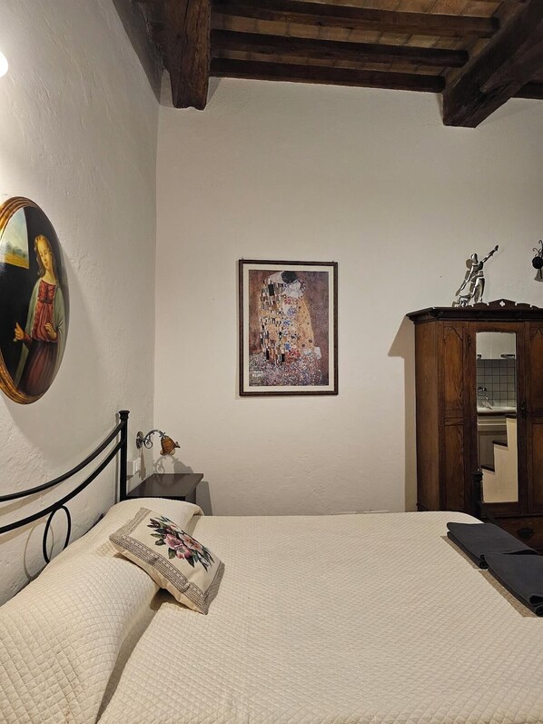 Une chambre à coucher avec un lit, une armoire en bois, un tableau et un miroir au mur.
