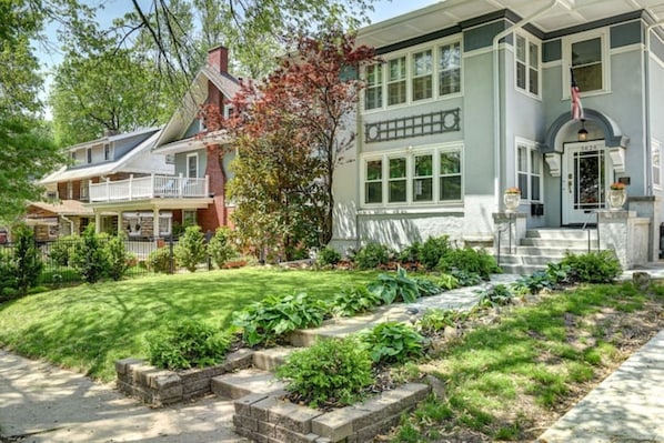 A two-story house with a front porch, a well-maintained lawn, and a brick pathway leading to the entrance.