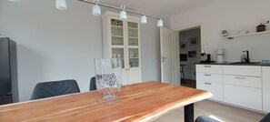 A modern kitchen with white cabinets, a wooden dining table, and a clear glass vase. - Top apartment / apartment in Kiel-Mitte (UKSH / CAU / stadium) (Kiel)