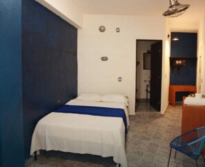 A bedroom with a bed, a chair, a desk, and a bathroom visible through an open door. - Estancia del Agua (Xul-Ha)