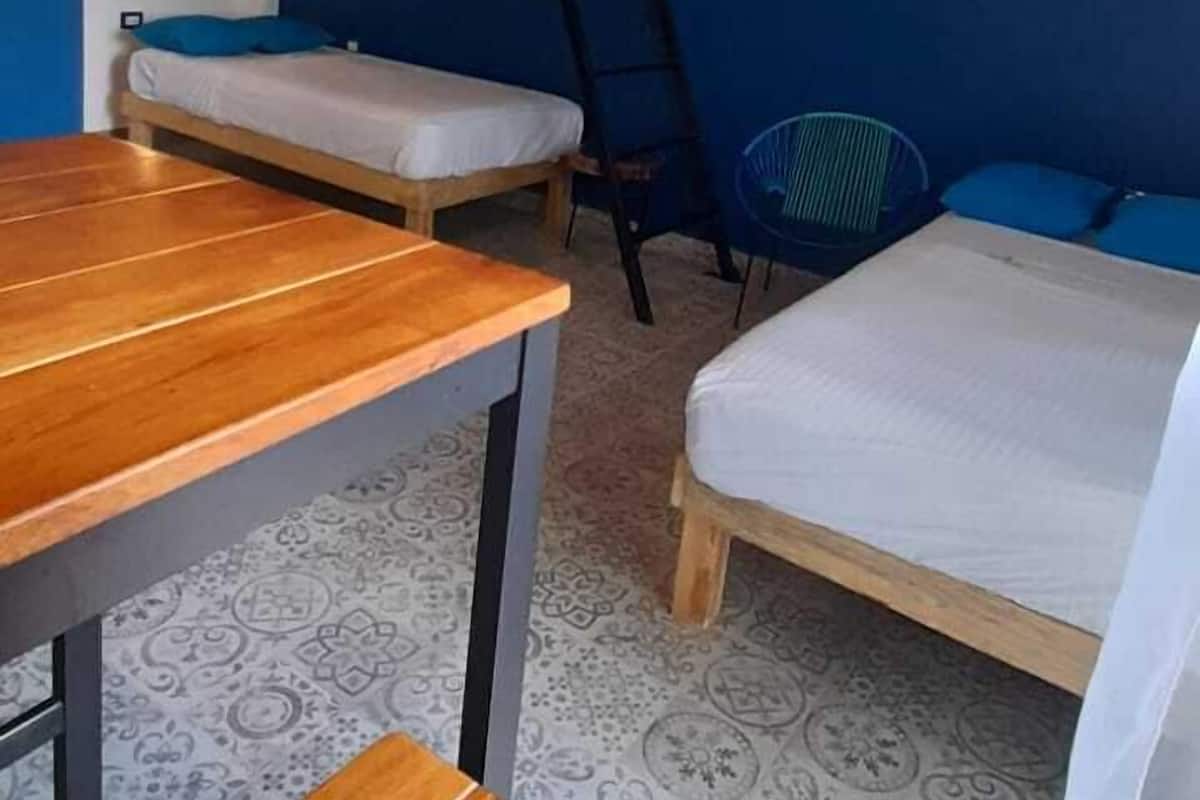 A bunk bed room with a wooden table, a chair, and a ceiling fan.