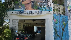A building with a mural of a woman and a bird, a sign reading "Estancia del Agua," and an ATV parked in front. - Estancia del Agua (Xul-Ha)