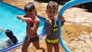 Dos niños jugando cerca de una piscina con un patio de piedra.