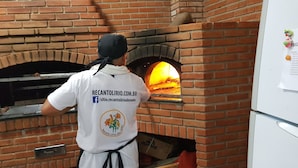 Una persona operando un horno de pizza de ladrillo.