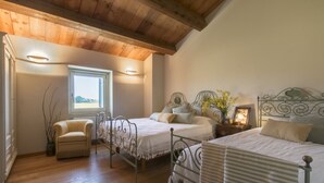 Un dormitorio con dos camas, techo de madera, una ventana y una silla.