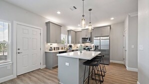 A modern kitchen with a central island, stainless steel appliances, and pendant lighting.