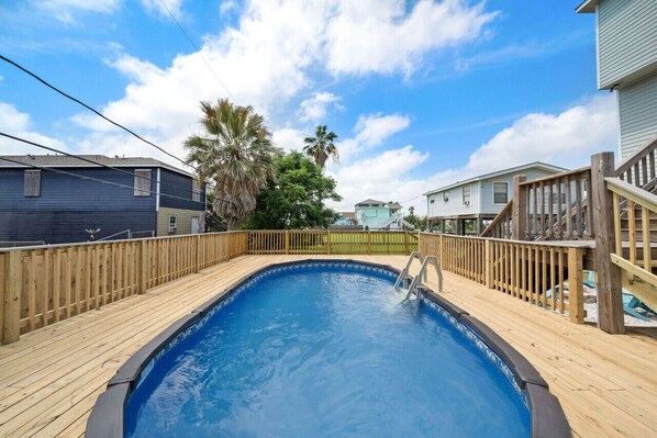 Une piscine avec une terrasse en bois et une clôture en bois.