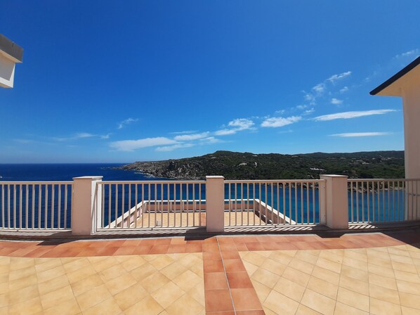 Un balcon avec vue sur la mer et les collines.