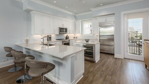 Une cuisine moderne avec des meubles blancs, des appareils en acier inoxydable et un îlot central doté de tabourets de bar.