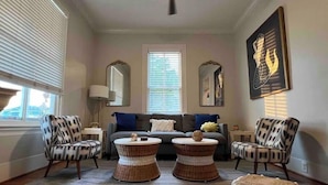 Un salon comprenant un canapé, deux fauteuils, une table basse et un tapis à motifs.