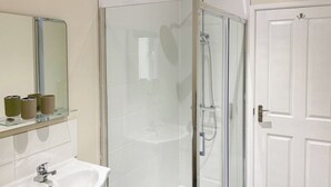 Une salle de bain avec une douche à parois de verre, un lavabo blanc et un miroir au-dessus du lavabo.