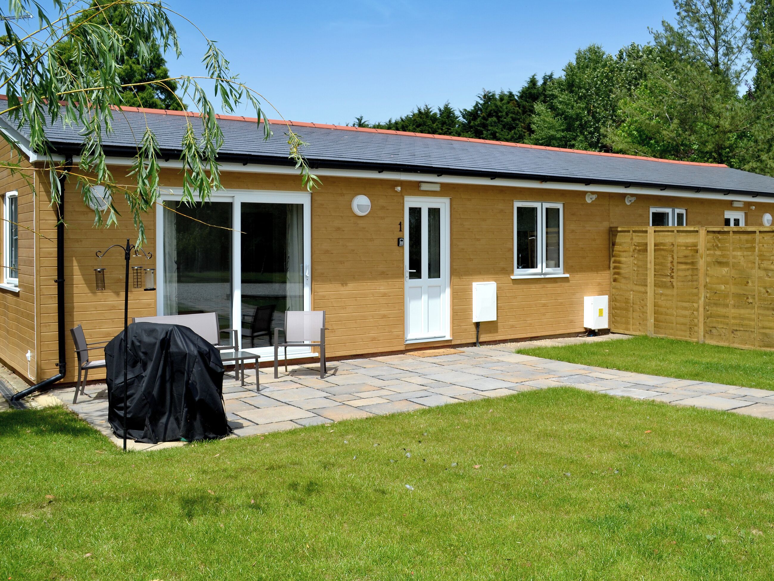 A single-story house with a patio, a covered barbecue area, and a sliding glass door leading to a deck.
