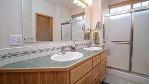 A bathroom with two sinks, a large mirror, and a shower.