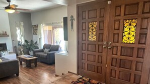 Amplia sala de estar con un gran puerta de madera, piso de baldosas y un sofá.