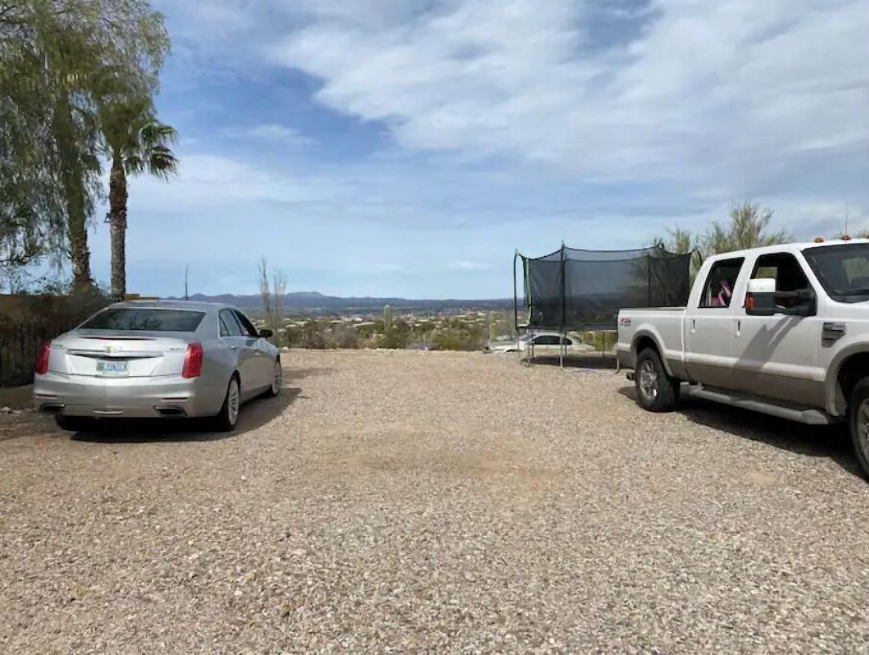 A gravel parking area with a silver sedan and a white pickup truck.