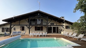 A two-story building with a wooden deck, a swimming pool, and outdoor seating. - Semi-detached house in gujan la hume (Gujan-Mestras)