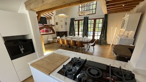 A kitchen with a central island, wooden ceiling beams, and a dining area with chairs and a table. - Semi-detached house in gujan la hume (Gujan-Mestras)