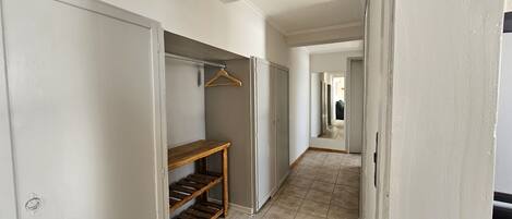 A narrow hallway with a wooden bench, a coat rack, and a wardrobe.
