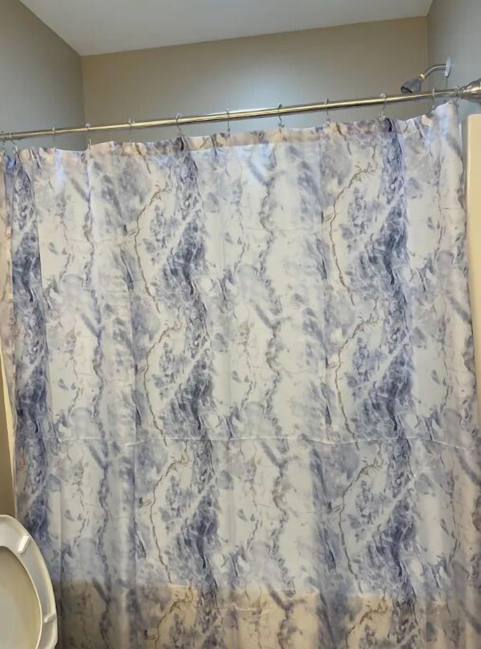 A bathroom with a shower curtain featuring a marble-like pattern.