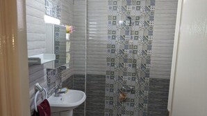 A bathroom with a white sink, a mirror, and a shower with patterned tiles.