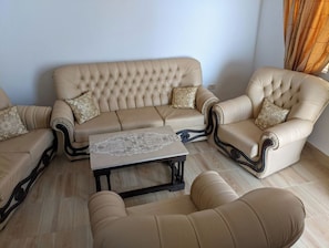 Un saló amb un sofà beix, una butaca a joc i una taula de centre amb una gornixa de punt.