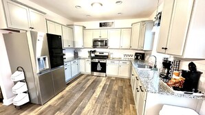 A modern kitchen with white cabinets, stainless steel appliances, and a granite countertop. - Quiet peaceful Stone mountain fun House with Pool ,Hot Tub￼ and vineyards near  (Traphill)