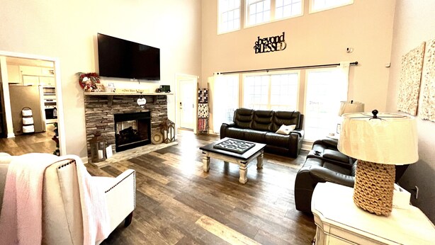 A spacious living room with a fireplace, a television, and a large window. - Quiet peaceful Stone mountain fun House with Pool ,Hot Tub￼ and vineyards near  (Traphill)
