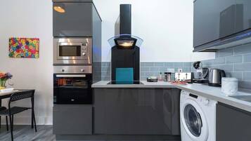 A compact kitchen with a built-in oven, microwave, and a washing machine.