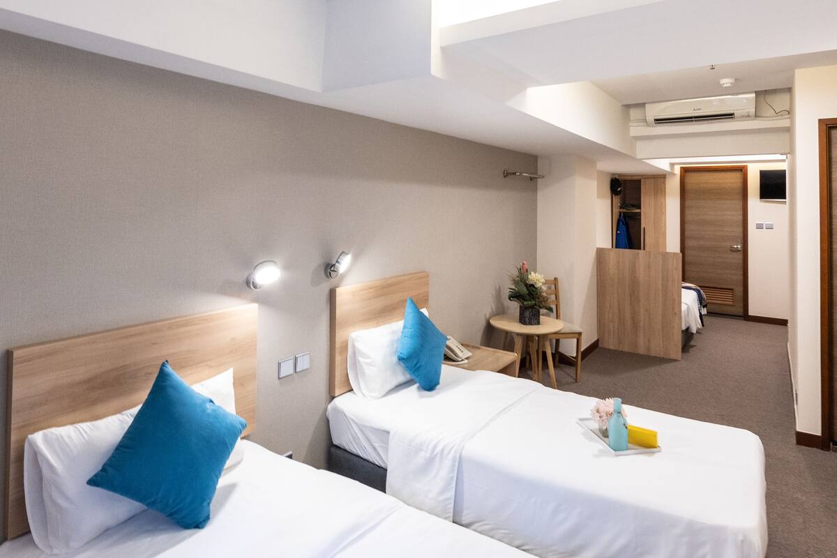 A hotel room with two beds, a small table with a chair, and a closet.