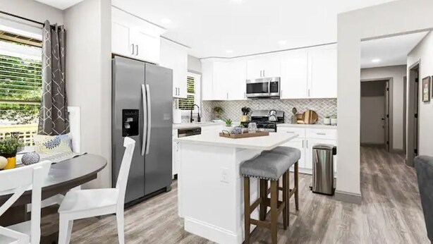 A modern kitchen with white cabinets, stainless steel appliances, and a central island with stools.