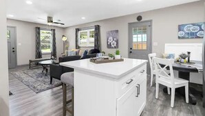 A modern kitchen with white cabinetry, a central island, and a dining area with a table and chairs.