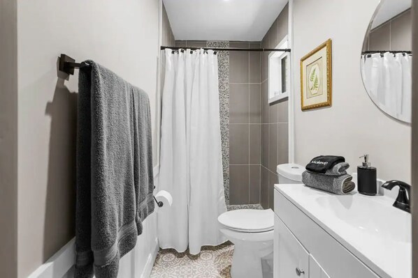 A bathroom with a toilet, sink, and shower curtain.