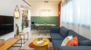 A modern living room with a TV, sofa, coffee table, and dining area.