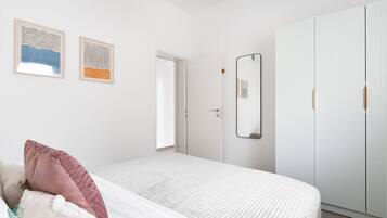 A bedroom with a bed, a wardrobe, and two framed artworks on the wall.