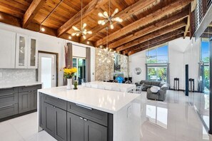 Una cocina moderna con una isla grande, muebles oscuros y una pared de acento de piedra.