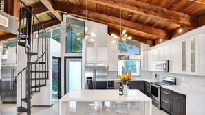A modern kitchen with a central island, stainless steel appliances, and a wooden ceiling. - Mid-Century Chic | Pool & Hot Tub | Skyview Loft (Fort Lauderdale)